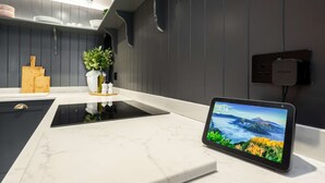 Una cocina moderna con una tablet que muestra un paisaje pintoresco, una tabla de cortar de madera y una planta en maceta.