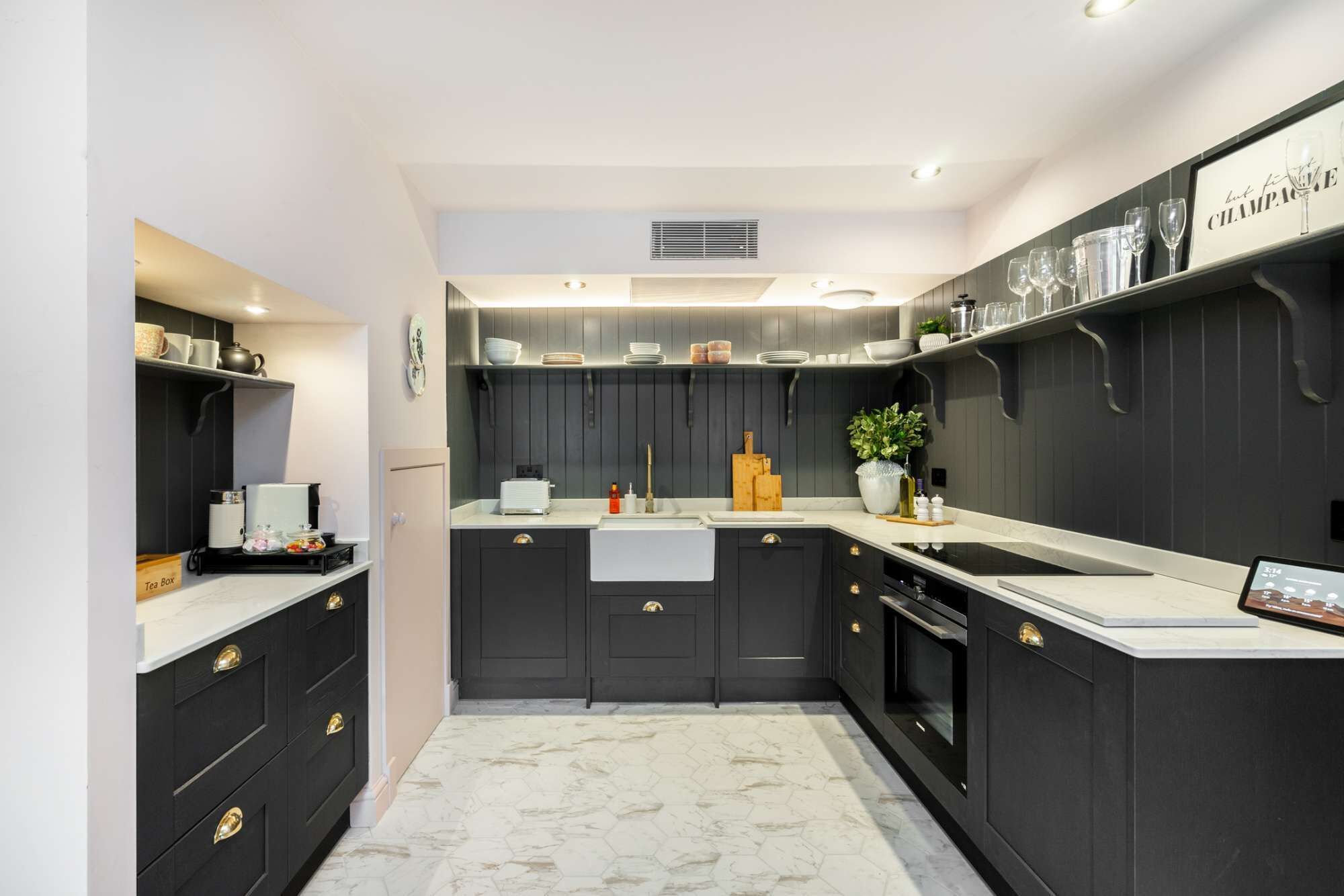 A modern kitchen with dark cabinetry, white countertops, and a marble floor.