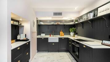 A modern kitchen with dark cabinetry, white countertops, and a marble floor.