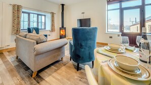 A cozy living room with a sofa, a blue armchair, a TV, and a fireplace. - 2 bedroom accommodation in Lampeter (Lampeter)