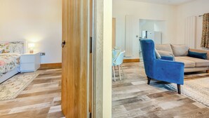 A room with a bed, a blue armchair, a sofa, a small table, and a door. - 2 bedroom accommodation in Lampeter (Lampeter)
