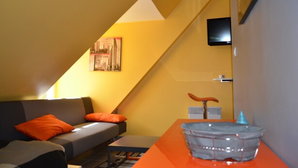 Un salon moderne avec un canapé, une table et un téléviseur fixé au mur.
