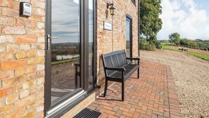 Un bâtiment en briques avec une porte en verre, un banc et un chemin de gravier.