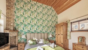 Une chambre à coucher avec un lit, une armoire en bois, une table de chevet, une lampe et une cheminée.