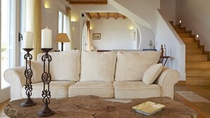 Un salon chaleureux avec un canapé beige, une table basse en bois et un escalier.
