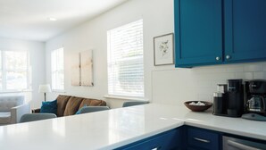 A modern kitchen with blue cabinets, white countertops, and a coffee maker. - Rest Easy : King Bed : Downtown & Ft. Jackson 2Bd 1Bth (Columbia)