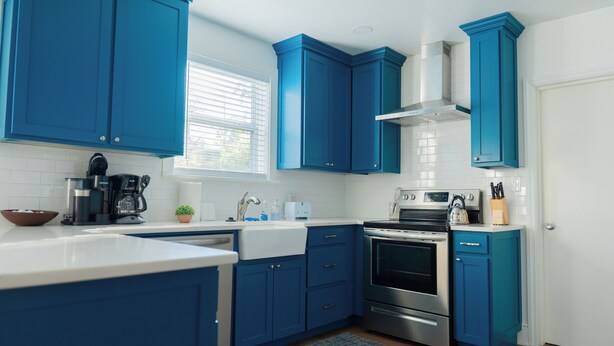 A modern kitchen with blue cabinets, a stainless steel stove, and a white countertop. - Rest Easy : King Bed : Downtown & Ft. Jackson 2Bd 1Bth (Columbia)