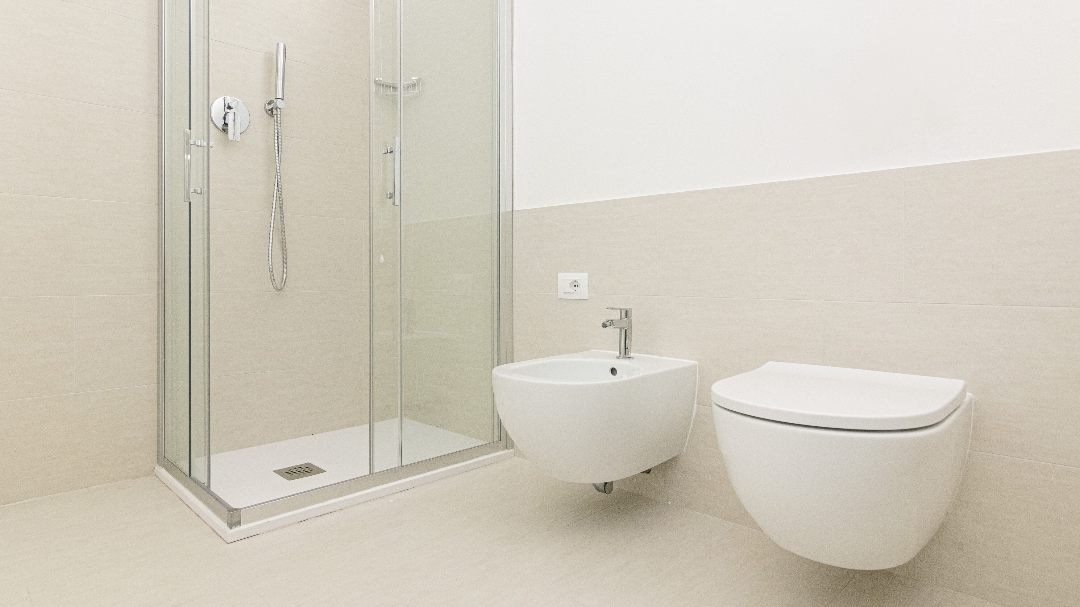 A modern bathroom with a glass-enclosed shower, a pedestal sink, and a toilet.