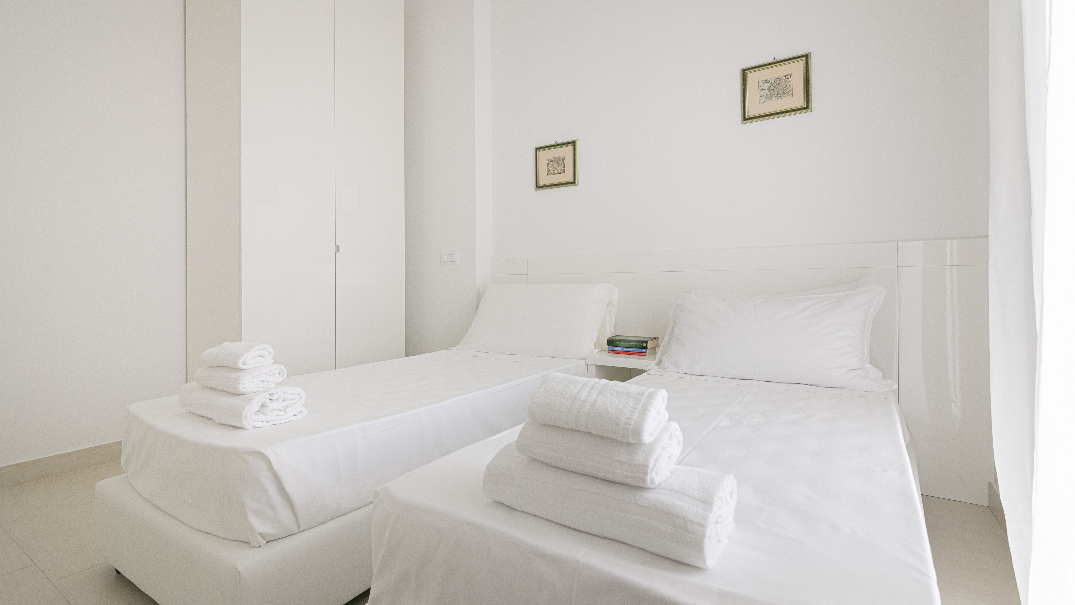 A hotel room with two beds, white bedding, and neatly folded towels.
