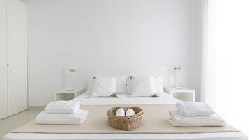 Een minimalistisch hotelkamer met een groot bed, twee nachtkastjes, een bedlamp en een geweven mand met handdoeken.