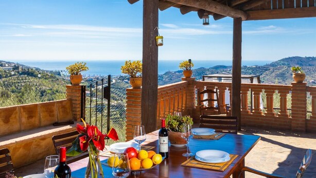 Una terraza con mesa lista para comer, con vistas a un paisaje pintoresco.