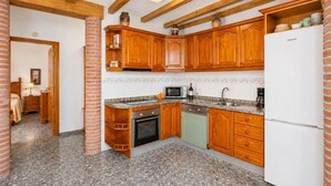 Une cuisine avec des meubles de rangement en bois, un four à micro-ondes, un évier et un réfrigérateur.