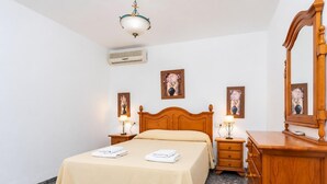 Une chambre à coucher comprenant un lit, des tables de chevet, une commode, un miroir et des œuvres d’art accrochées au mur.