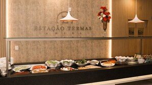 A buffet area with various dishes and a wall with the text "ESTAÇÃO TERMAS." - Estação Termas Hotel (Piratuba)
