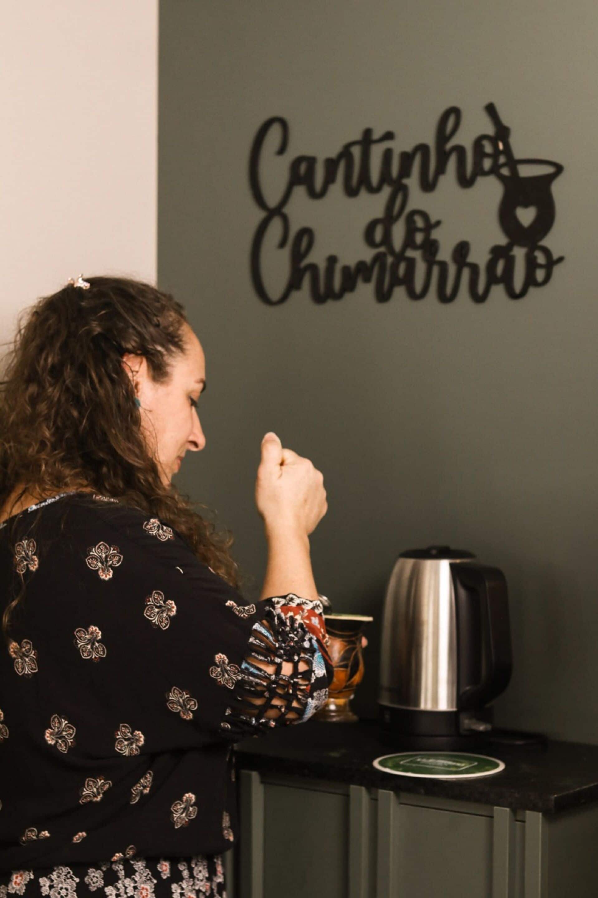 A person standing in front of a wall with a sign that reads "Cantinho do Churrasco".