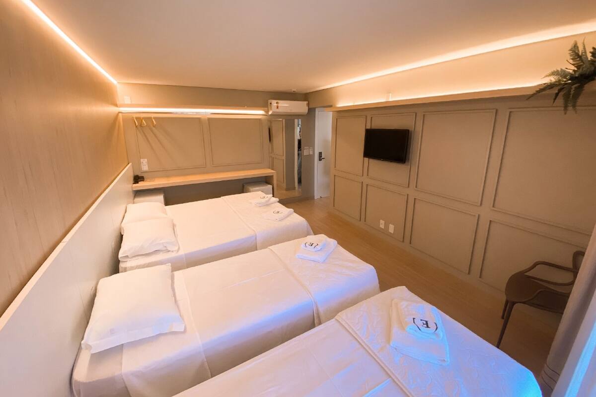 A hotel room with two beds, a TV, and a shower area.