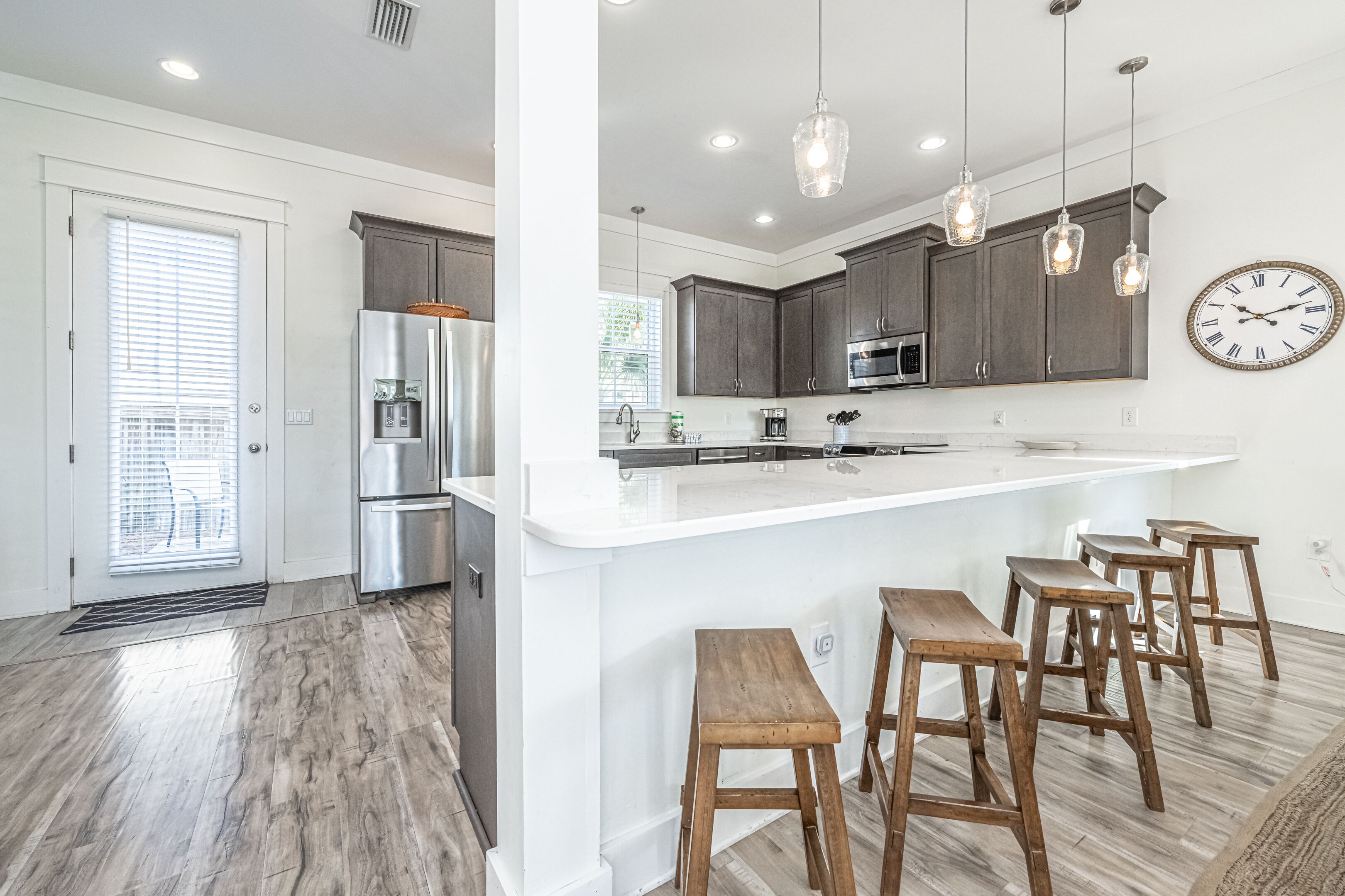A modern kitchen with a large island, bar stools, and pendant lighting.