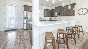A modern kitchen with a large island, bar stools, and pendant lighting. - Walk to the Beach ~ Golf Cart ~ Communal Pool (Santa Rosa Beach)