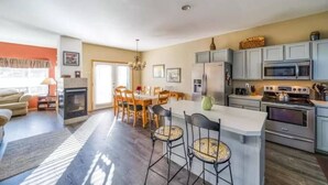Een moderne keuken met grijze kastjes, roestvrijstalen apparatuur en een centraal kookeiland met barstoelen.