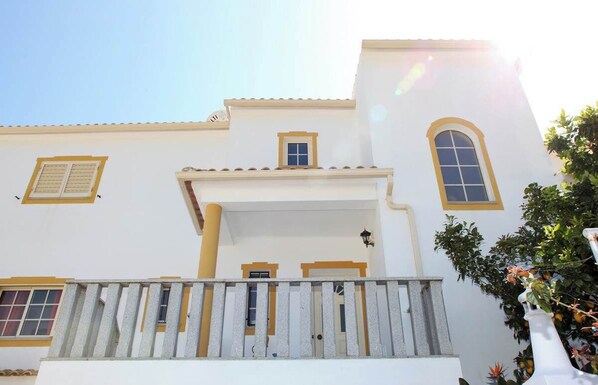 A white building with yellow trim and a balcony.