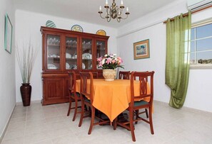 A dining room with a wooden table and chairs, a cabinet with glass doors, and a vase with flowers.