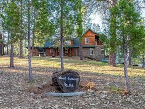 A lodge with a stone exterior, surrounded by trees and a clear sky.