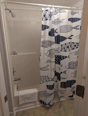 A shower with a white curtain featuring a fish pattern.