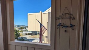 Une fenêtre donnant sur un immeuble, un drapeau américain et une décoration représentant un oiseau fixée au mur.
