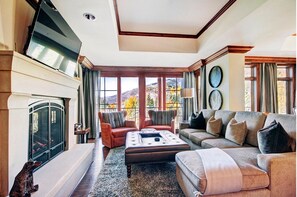 Cozy up by the fireplace in this stylish living room with a sofa and armchairs, offering a view of the outdoors.