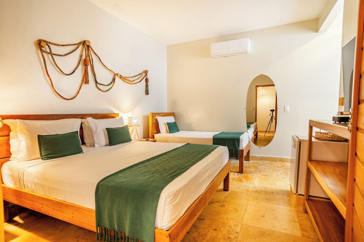 Habitación de hotel con dos camas, un espejo, un banco de madera y una mesita.