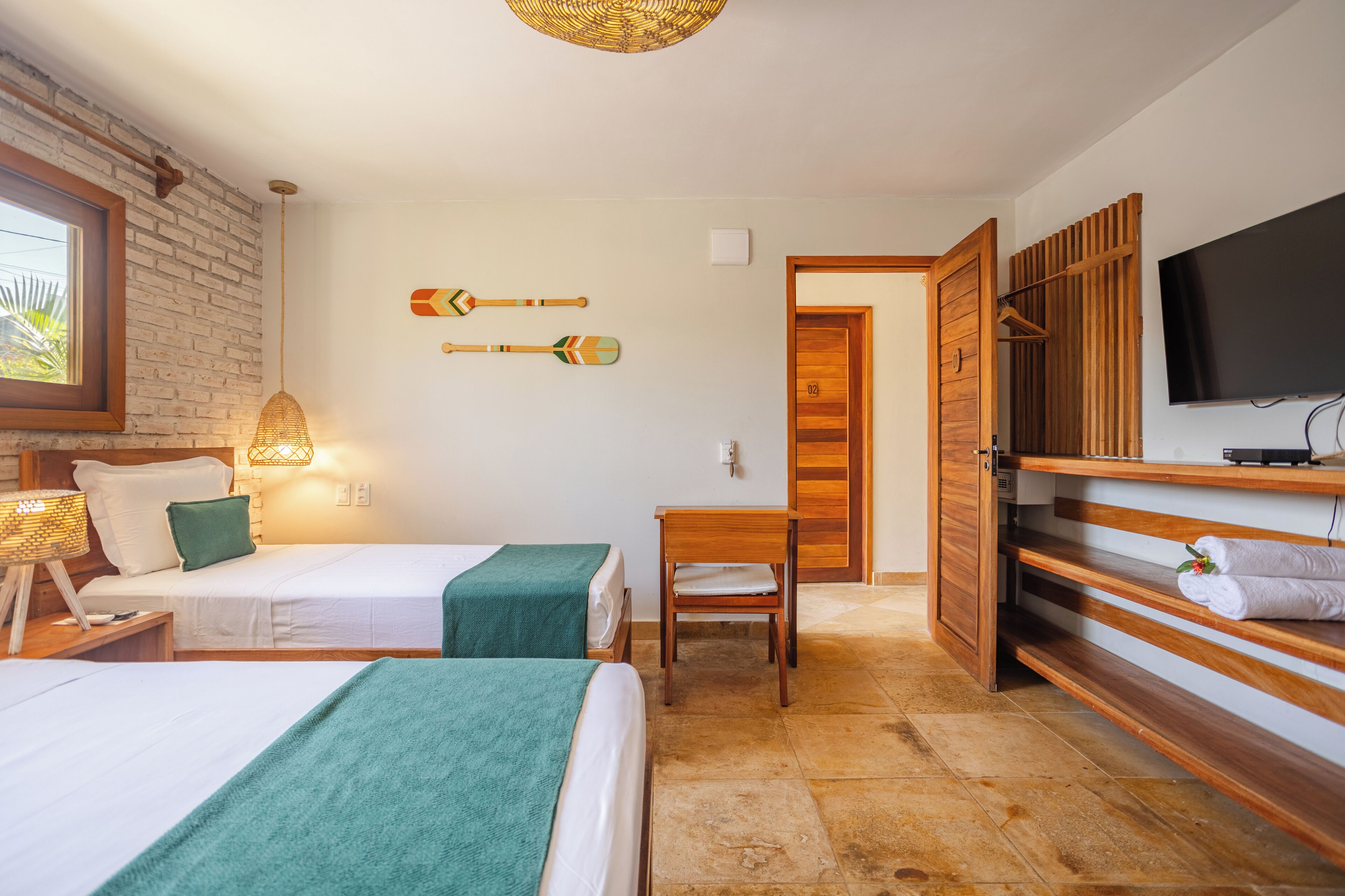 Una habitación de hotel con dos camas, un armario de madera, televisión y televisor de pared.