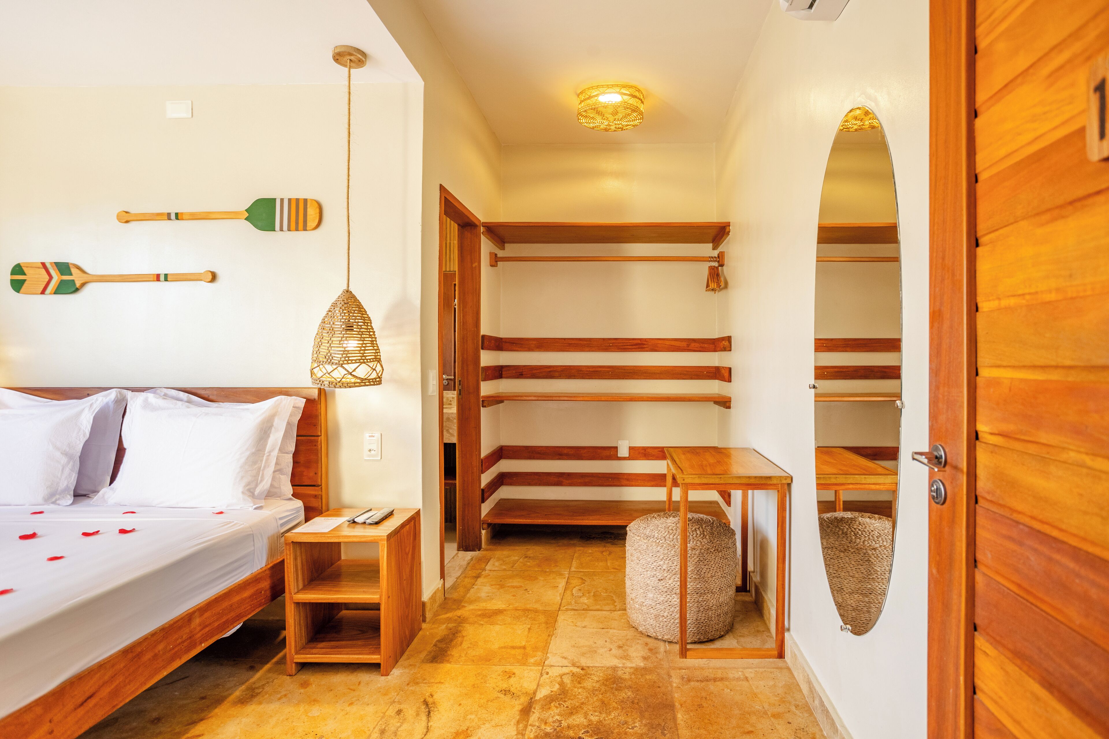 Een hotelkamer met een bed, houten meubels, een hanglamp en een kleine tafel.