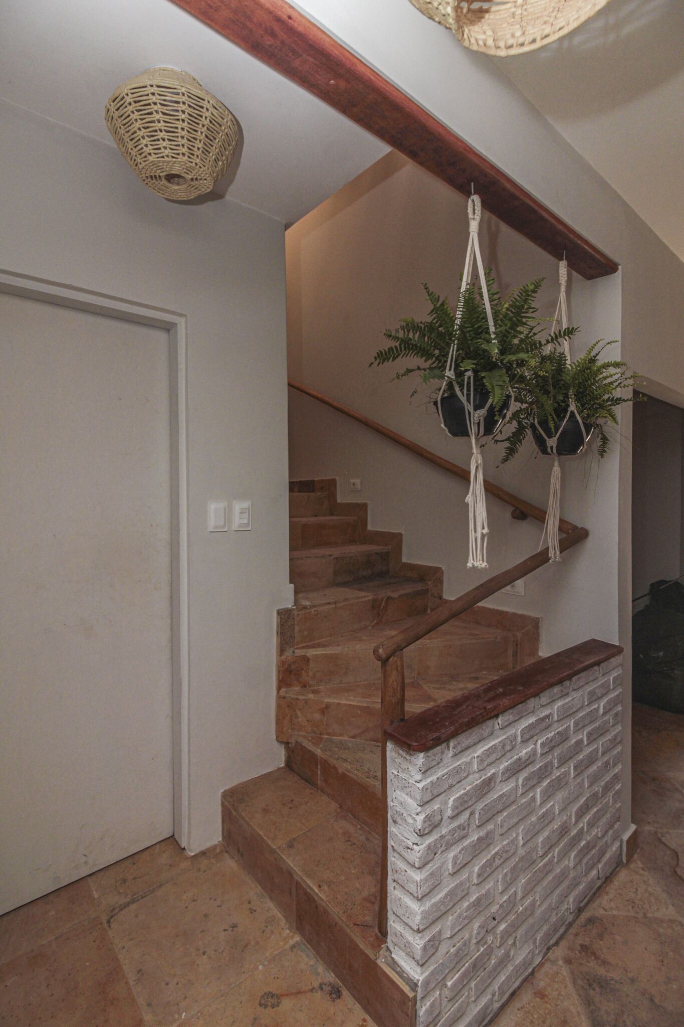 Un escalier avec une rampe en bois et un mur en briques blanches.