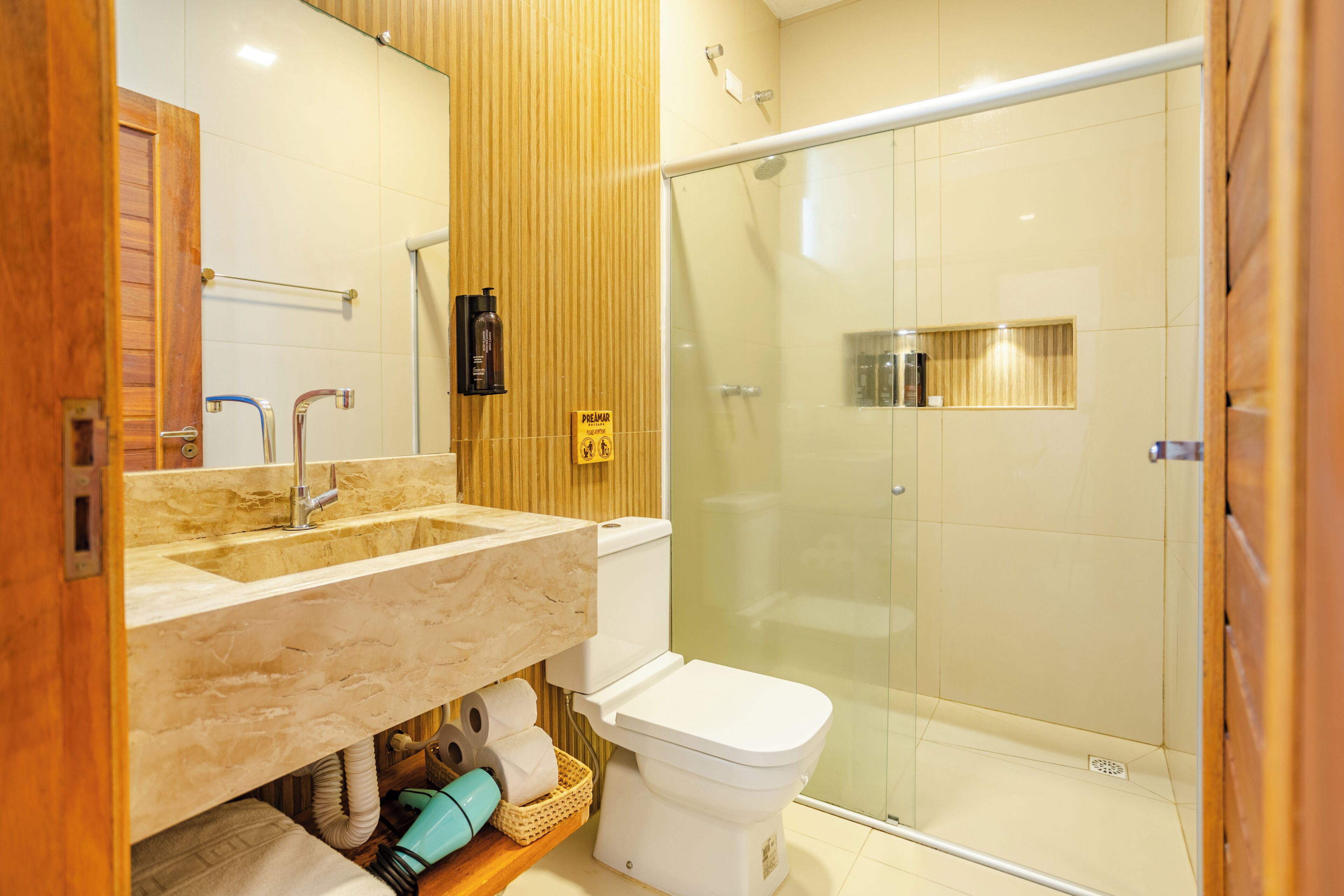 Een badkamer met een houten wastafelmeubel, toilet, douchecabine en een handdoekhouder.