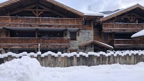 A chalet-style building with stone and wood construction, featuring balconies and a stone entrance. - Lapia104 : Splendid one bedroom + cabin (MORZINE)