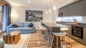 A modern kitchen with a central island, bar stools, and a built-in oven. - Lapia104 : Splendid one bedroom + cabin (MORZINE)