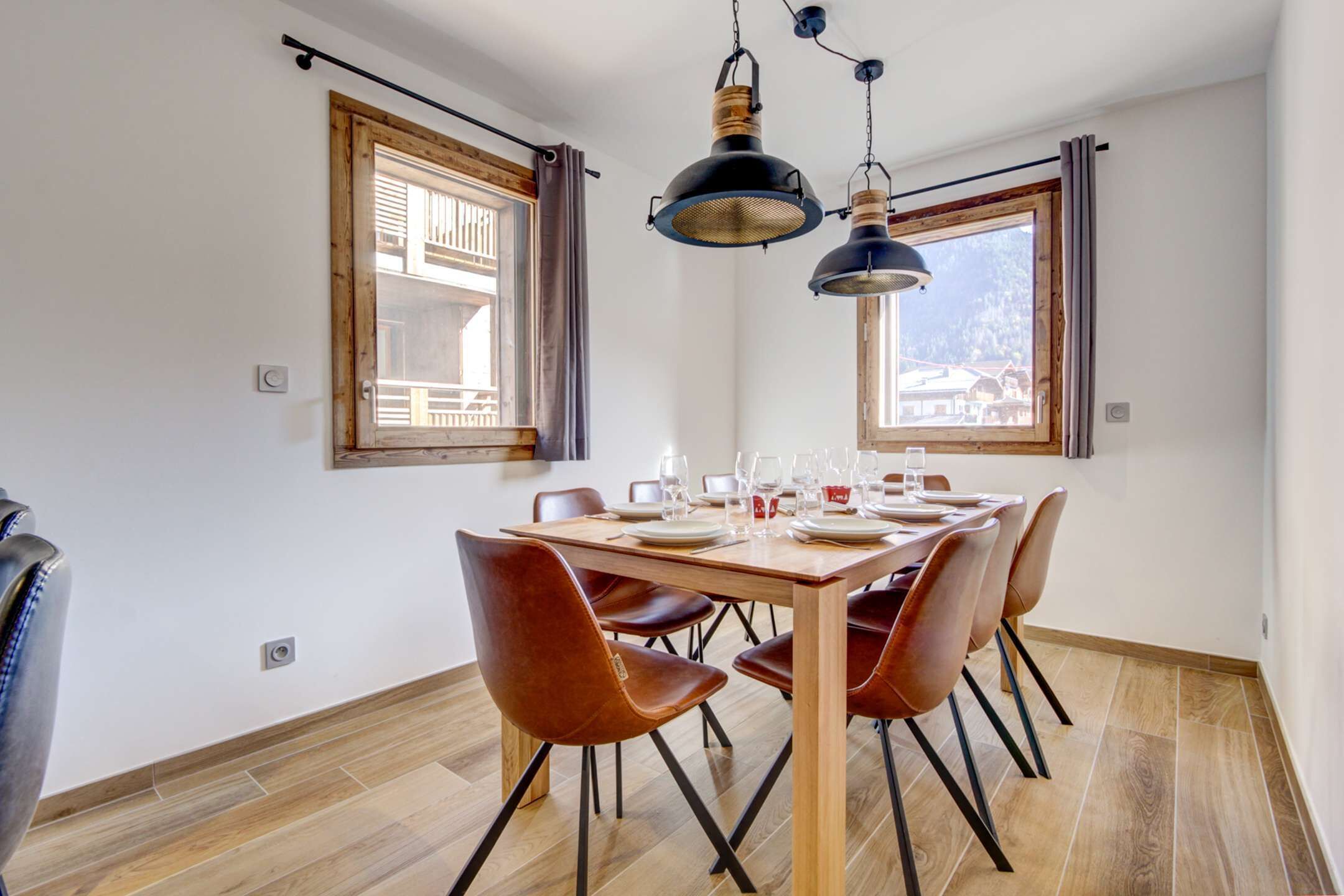 A dining area with a wooden table set for four, surrounded by brown chairs.
