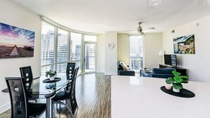Una sala de estar moderna con una mesa de comedor de vidrio, un sofá y un televisor.