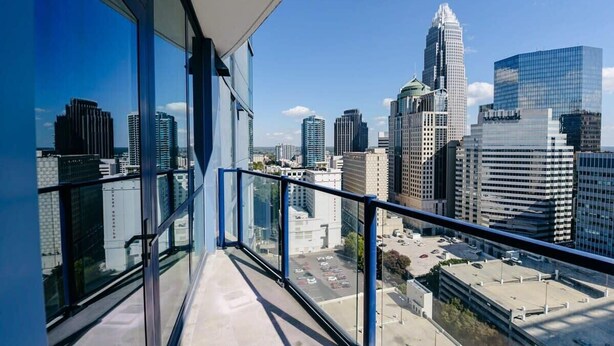 Ein Hochhaus mit Stadtblick von einem Balkon mit Glasgeländern.