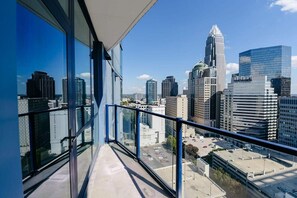 Un edificio alto con vistas a la ciudad desde un balcón con barandilla de vidrio.