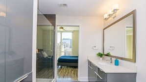 A modern bathroom with a large mirror, a sink, and a shower area. - Charlotte Uptown Fully Furnished Apartments (Charlotte)