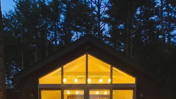 Une cabine dotée de grandes fenêtres, d’un balcon et d’un fauteuil.