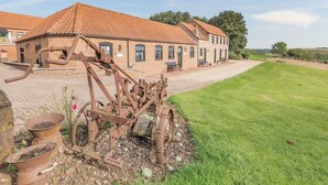 A rustic building with a red-tiled roof and brick walls, a gravel driveway, and a grassy lawn. - Juice Trump - UK36670 (Belchford)