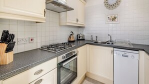 A kitchen with white cabinets, a gas stove, an oven, a dishwasher, and a skylight. - Juice Trump - UK36670 (Belchford)