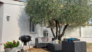 Un área de estar al aire libre con una parrilla, una planta en maceta y un árbol.