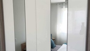 Un dormitorio con cama, mesita de noche y espejo.