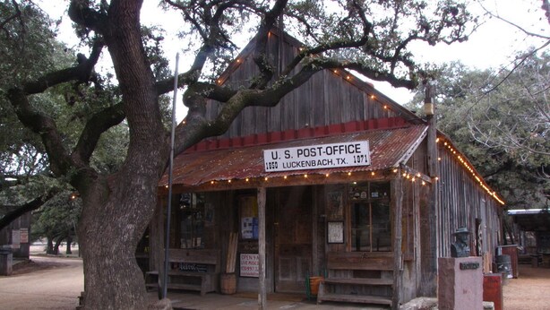 Un edificio rústico de oficina postal estadounidense con un cartel que indica su ubicación en Lichtenbach, TX, establecido en 1971.