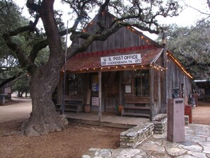 Un bâtiment rustique abritant le bureau de poste américain de Lichtenbach, au Texas, avec une enseigne indiquant son emplacement. Il a été construit en 1971.