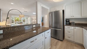 Una cocina moderna con encimeras de granito, electrodomésticos de acero inoxidable y armarios blancos.