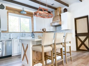 A modern kitchen with wooden accents, a large island with bar stools, and a farmhouse-style door.